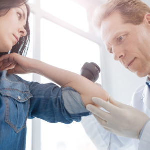A dermatologist inspects a patient's skin for signs of skin cancer