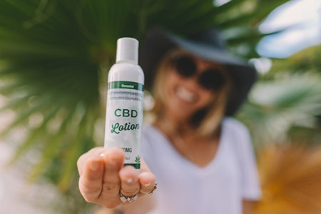 Woman holding CBD lotion bottle