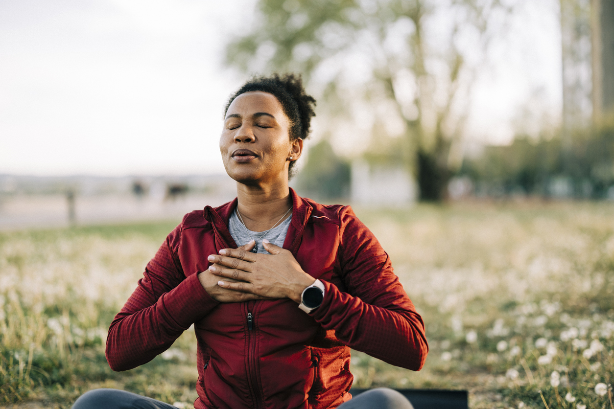 woman holding her hands over her chest and closing her eyes while struggling due to environmental allergies
