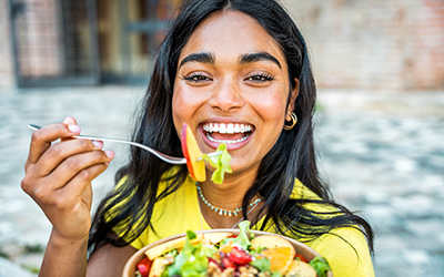 Young happy woman eating healthy salad with green fresh ingredients