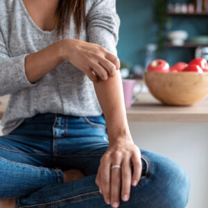 woman sitting at her counter while itching her eczema during fall season