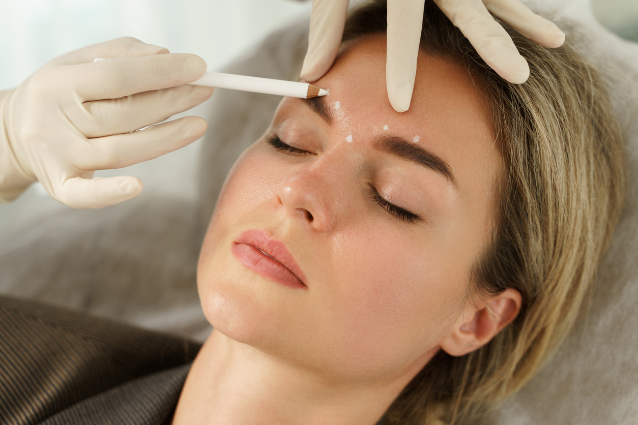 Doctor making marks on client's face before natural-looking injections in aesthetics medical clinic