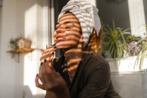 young woman putting skincare on her face during fall time