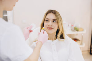 woman smiling at the dermatologist holding a syringe, symbolizing the best cosmetic treatments
