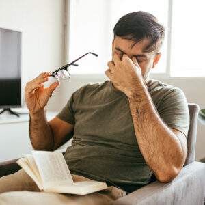 man holding his glasses and his face due to sinus pressure and allergy headache
