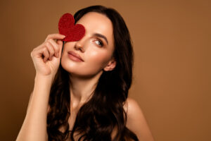 portrait of a woman holding up a heart while posing for valentine's date night skincare