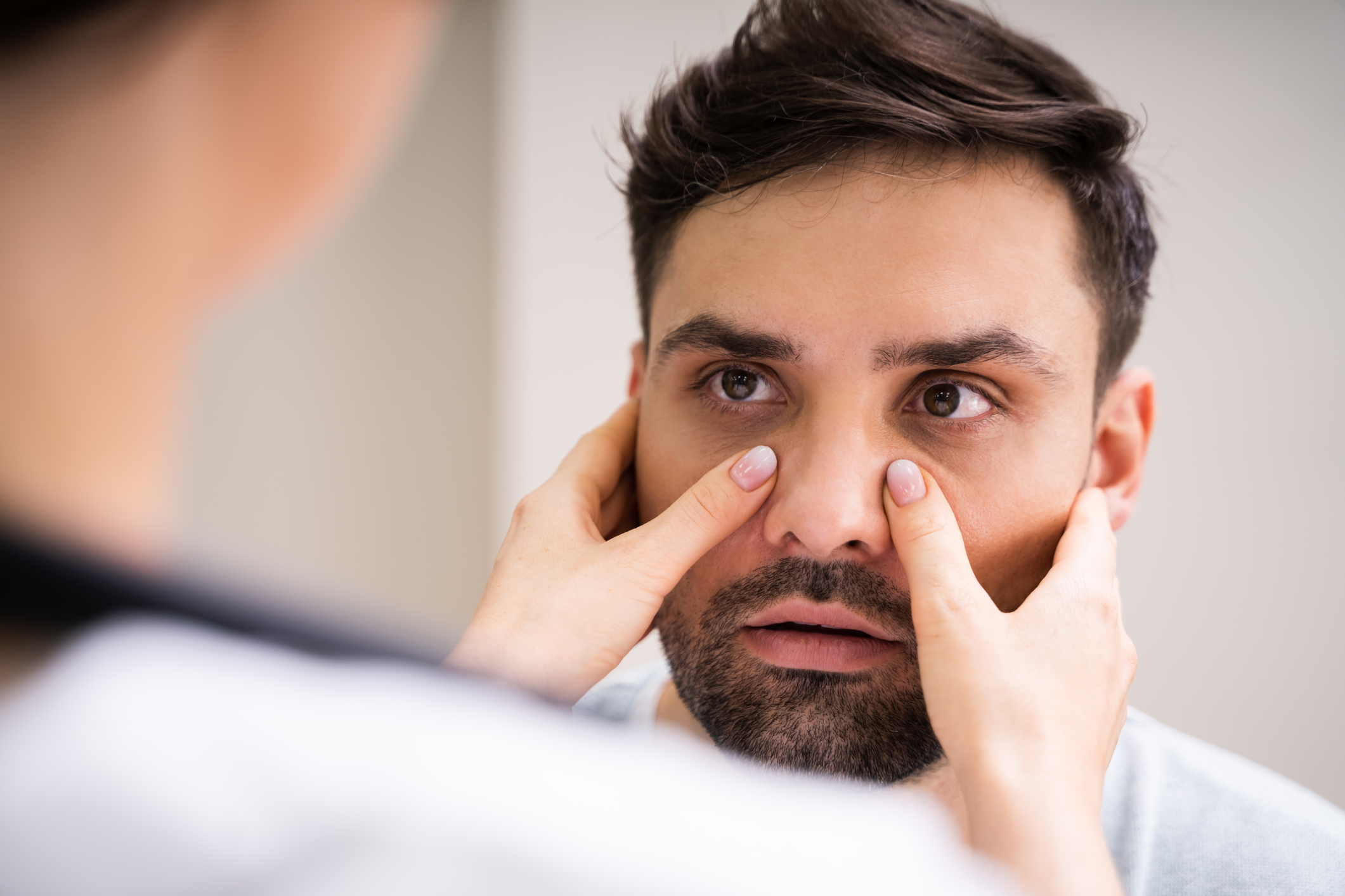 Close up of an allergist with his hands on a patient's face to decipher and diagnose allergies vs sinus infection