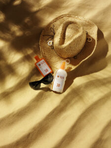 Sun hat with sun protection and sunglasses, on a beach with palm tree shadows.