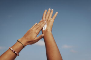 Close-up of hands applying sun cream under a bright blue sky in Maldives
