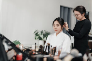 Asian beautician styling hair of bride during pre-wedding preparation in studio workspace. elegance, beauty, and professional occupation.