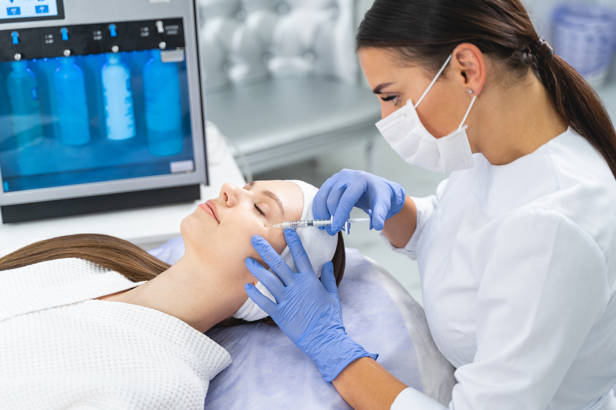 Concentrated professional female dermatologist giving an injection to a young patient with a disposable syringe