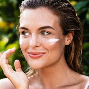 Outdoor portrait of beautiful woman with moisturizing cream under her eyes