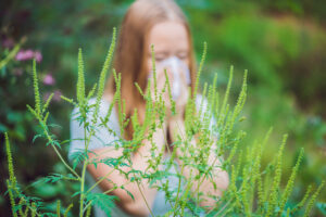 Young woman sneezes because of an allergy to ragweed.